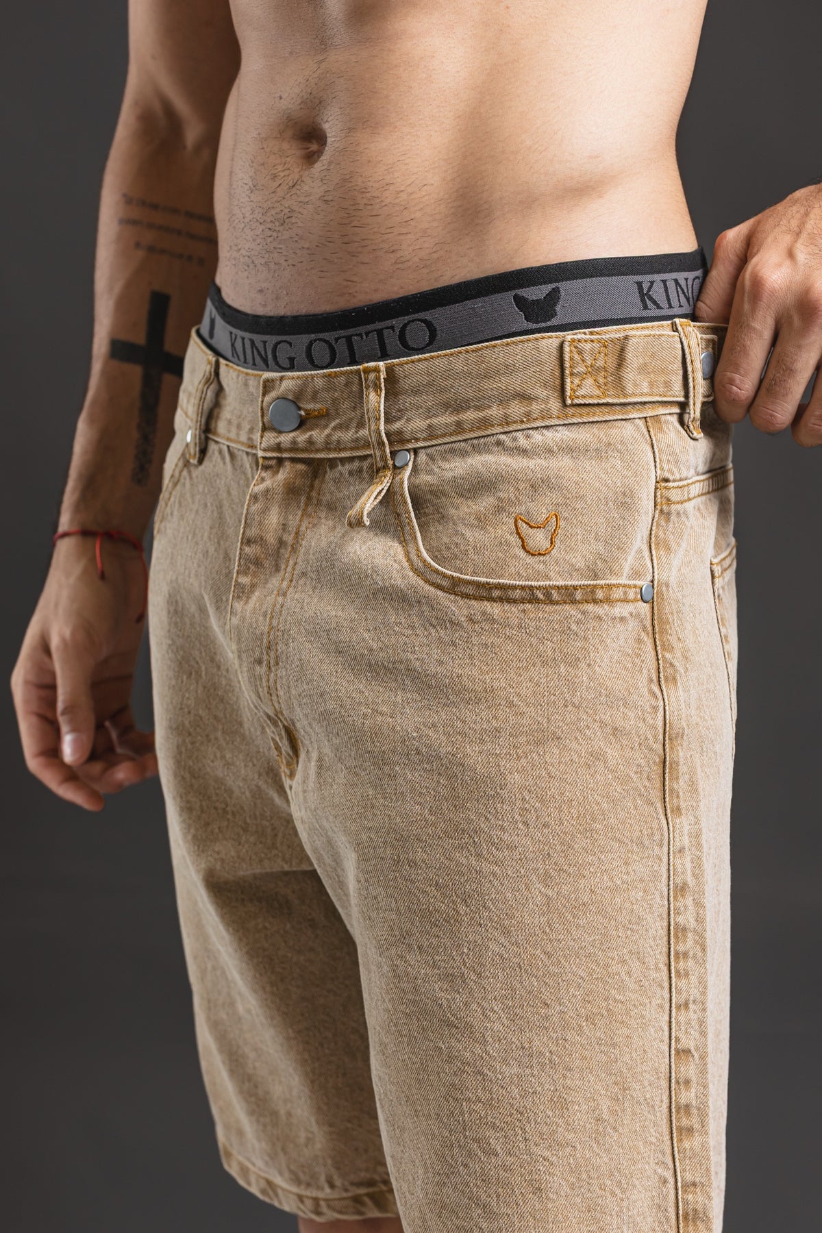 Bermuda OTTO Camel, detalle del bulldog bordado y el ajuste lateral de la cintura